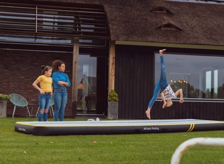 3 girls practicing gymnastics in garden on inflatable AirTrack spark