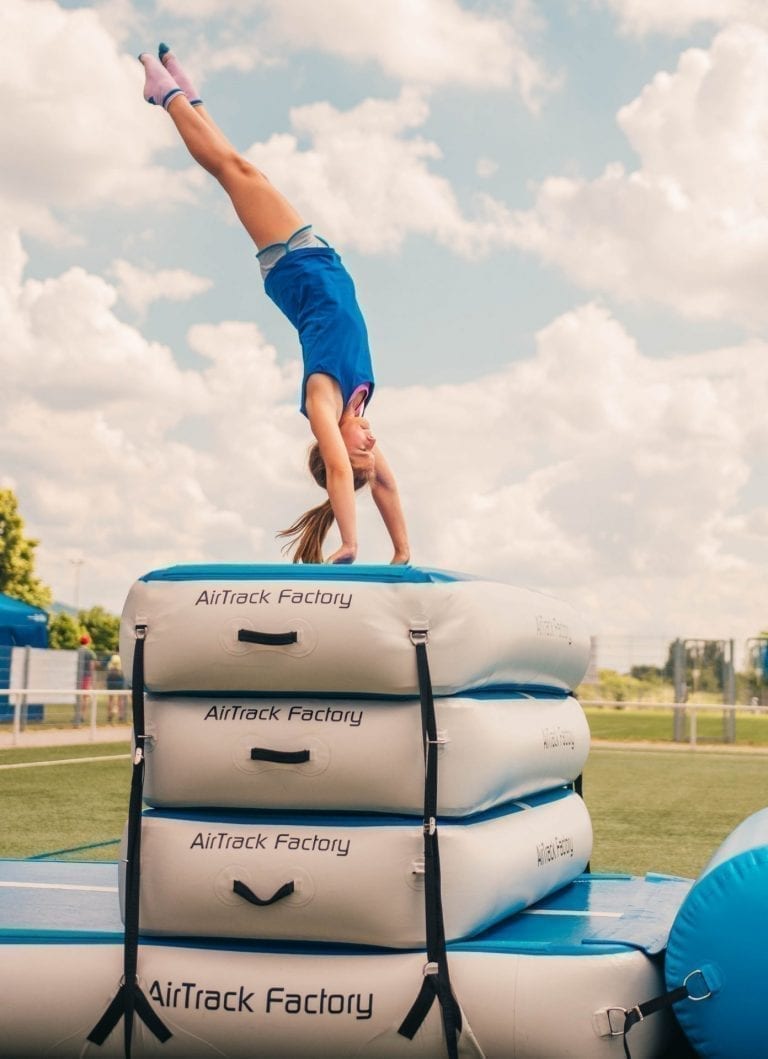 Gymnast with blue shirt performing a handstand outside