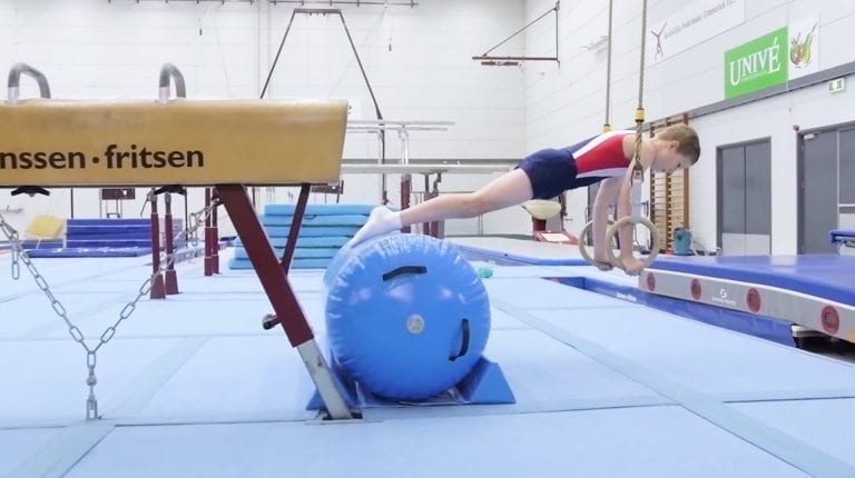 Boy gymnast leaning on AirRoll in gymnastic rings