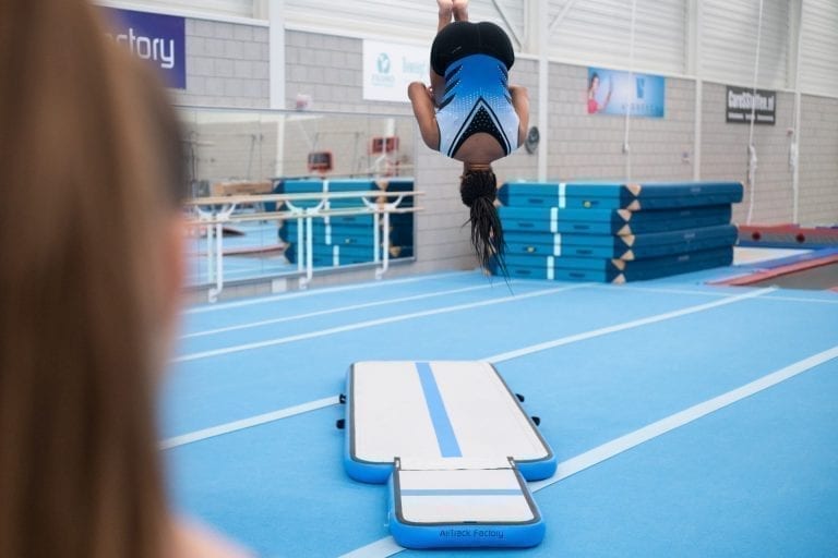 Girl gymnast jumping high on inflatable training set