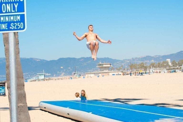 man jumping high on airtrack p3 on venice beach